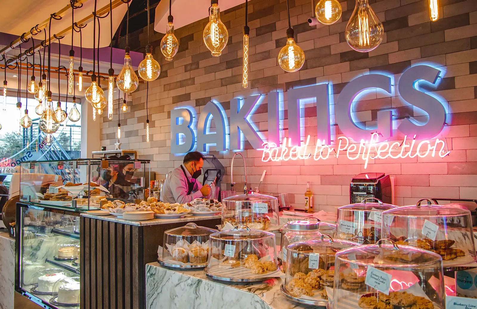 Barra y vitrina de postres con el letrero de neón de Bakings
