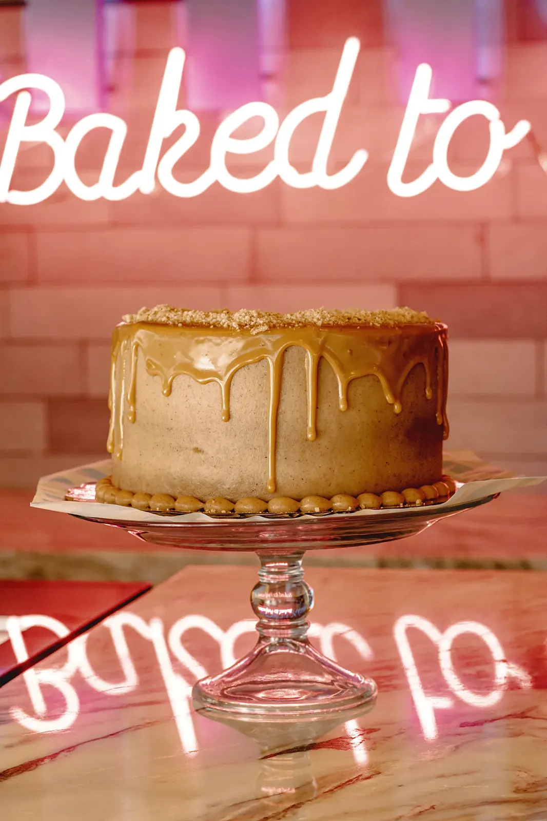 Pastel de caramelo frente al letrero de neón de Bakings