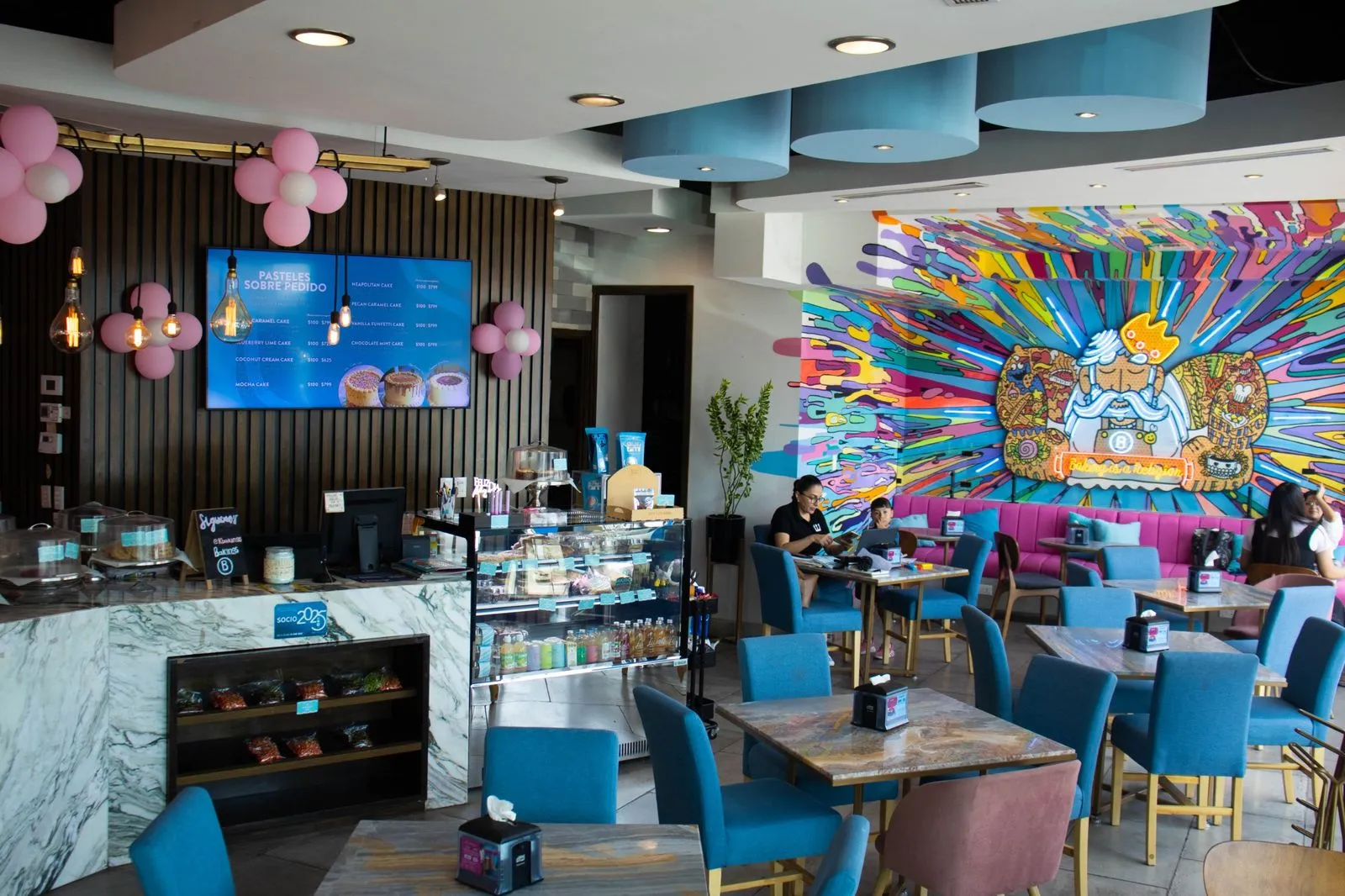 Interior de Bakings con mesas y mural de colores